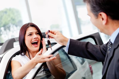 Salesman handling keys to a woman after buying a car